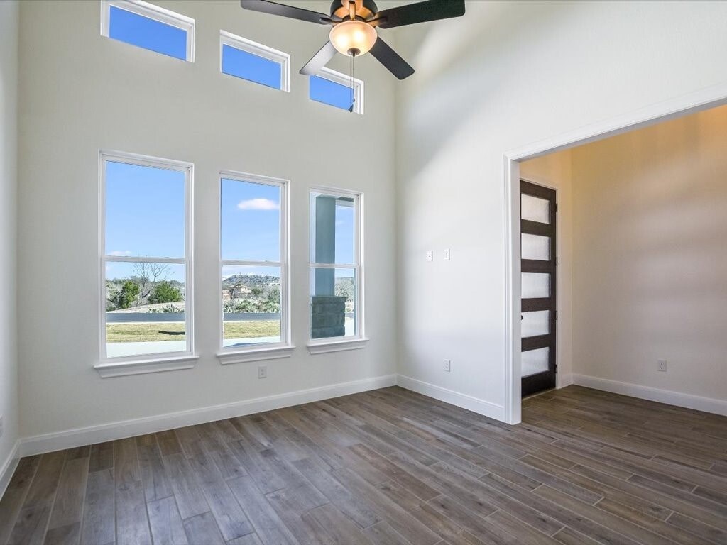A room with a ceiling fan and three windows.