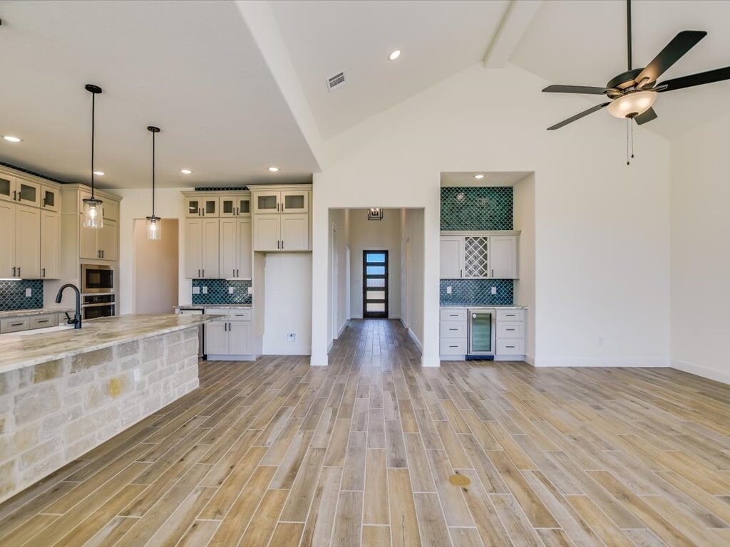 A spacious kitchen with wooden floors and a ceiling fan.