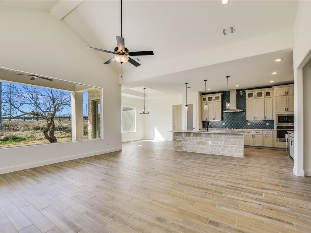 A spacious kitchen and living room with wooden flooring and a ceiling fan.