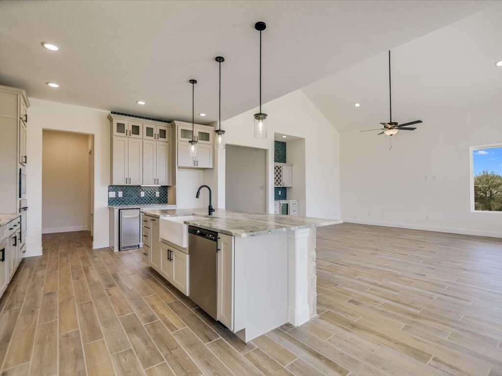 A modern kitchen with wooden floors and white cabinetry.