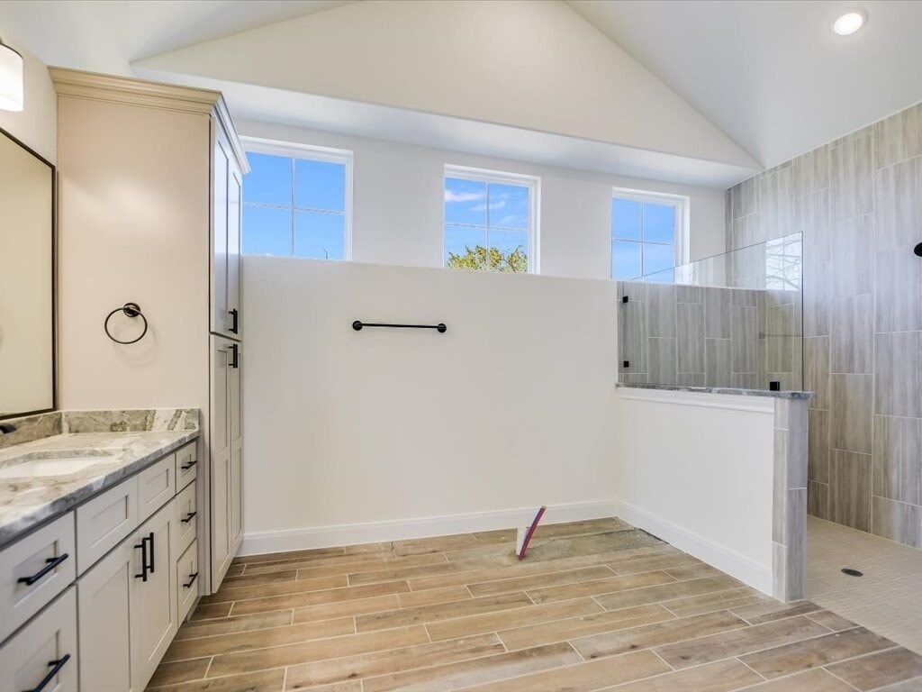 A bathroom with a marble countertop and wooden flooring.