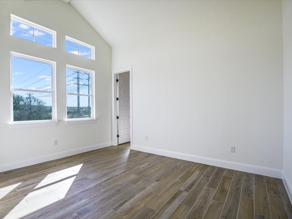 A room with wooden flooring and a door leading to another room.