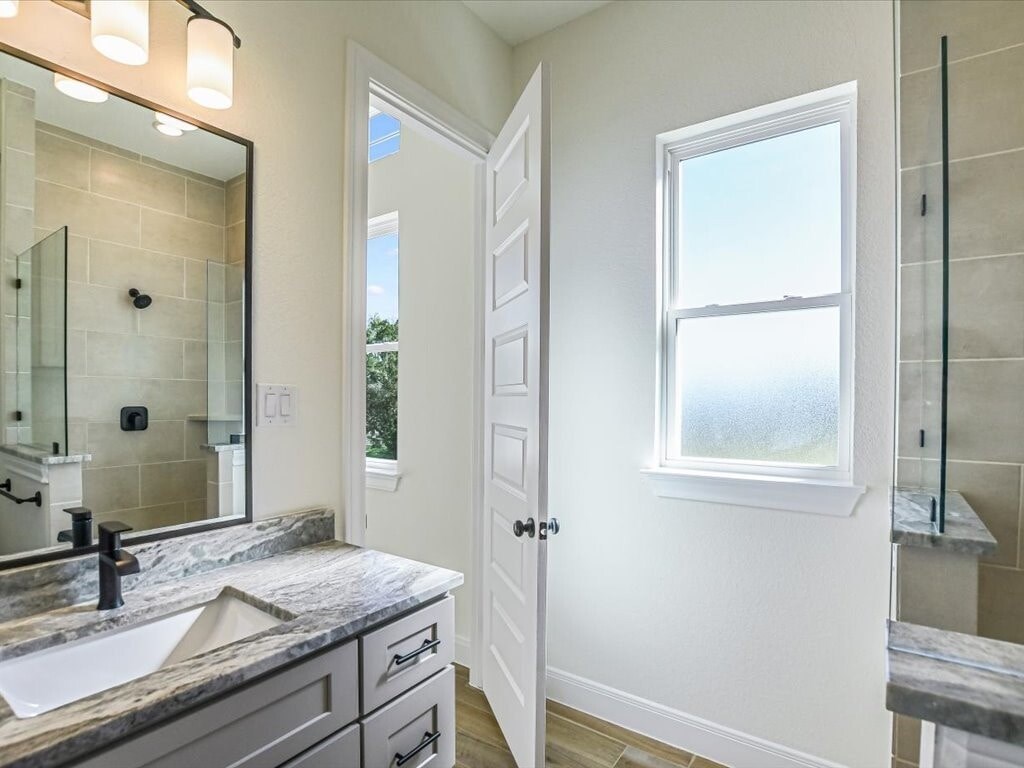A bathroom with a sink, mirror, and a window.