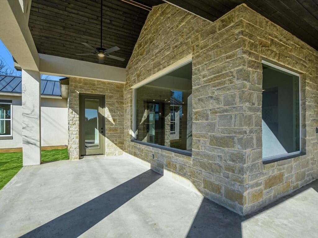 A modern house with a stone exterior and a large glass window.