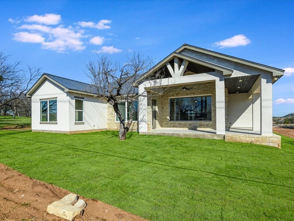 A modern house with a large front yard and a tree.