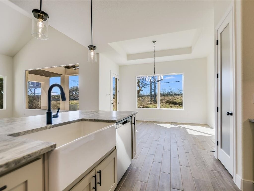 A kitchen with a marble countertop and wooden flooring.