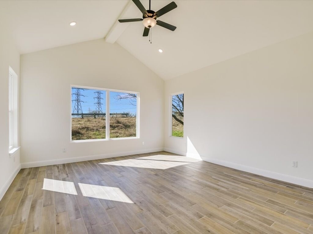 A room with a ceiling fan and a large window overlooking a field.