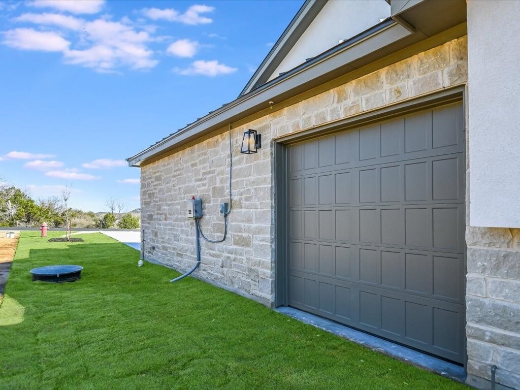 A house with a grey garage door and a stone wall.