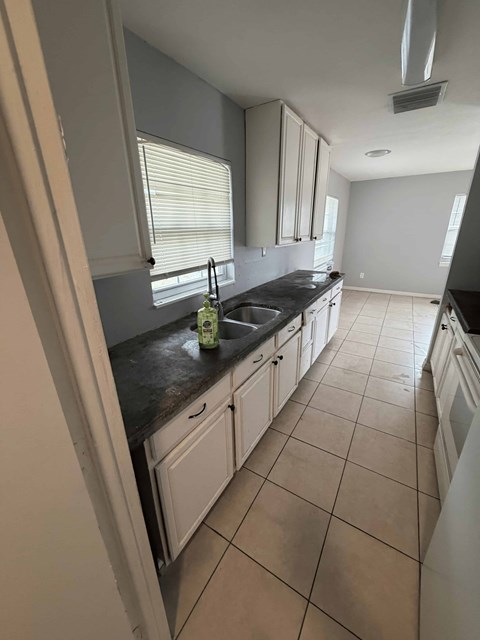 A kitchen with white cabinets and a black countertop.