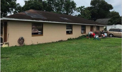 A house with a brown roof and a white wall with a hose hanging on it.