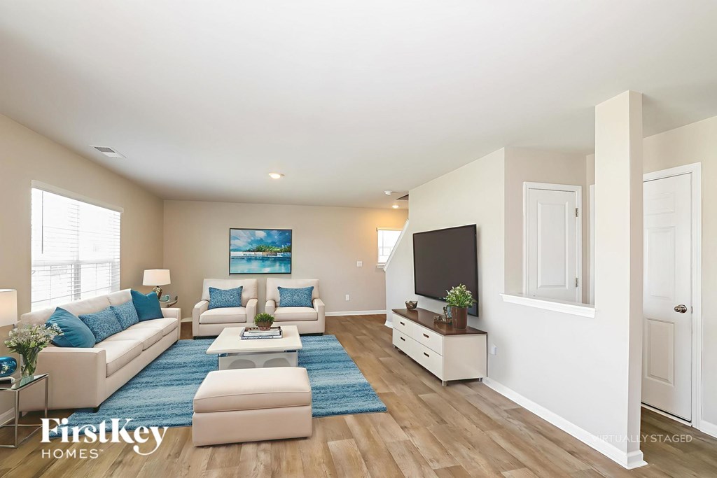 A living room with a white couch and a blue rug.