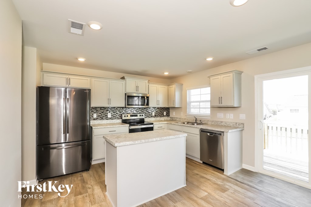 A kitchen with a stainless steel refrigerator and a white island.