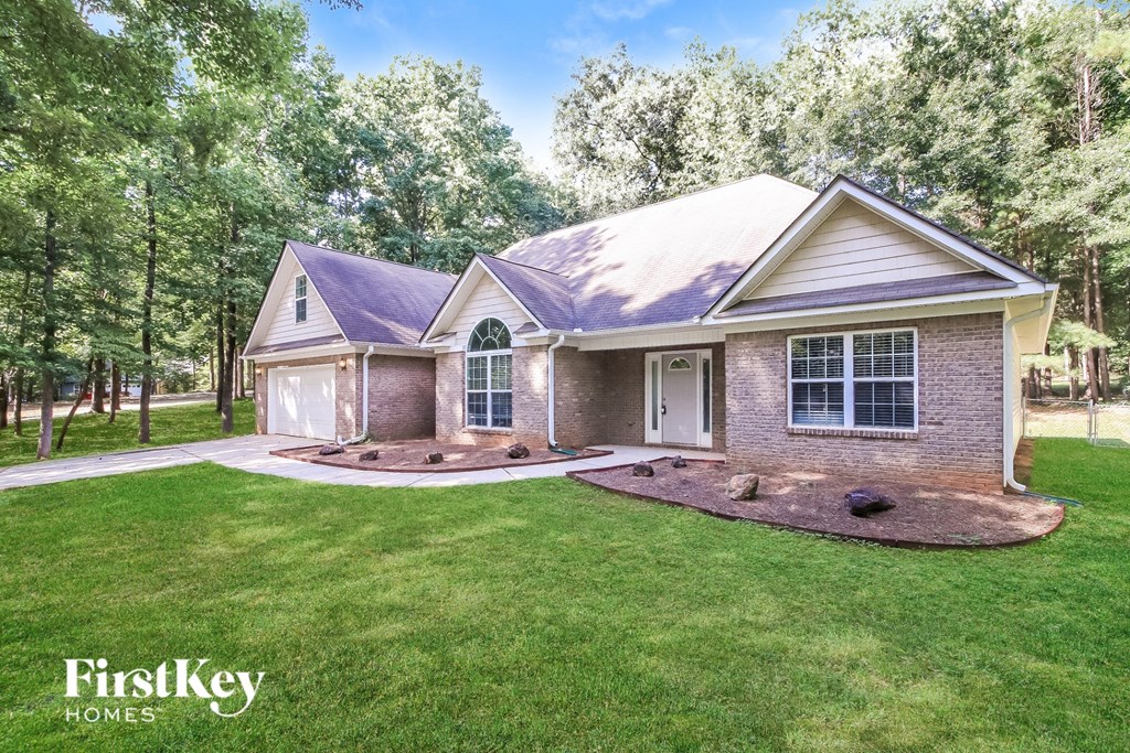A house with a well-manicured lawn and trees in the background is for sale by FirstKey Homes.