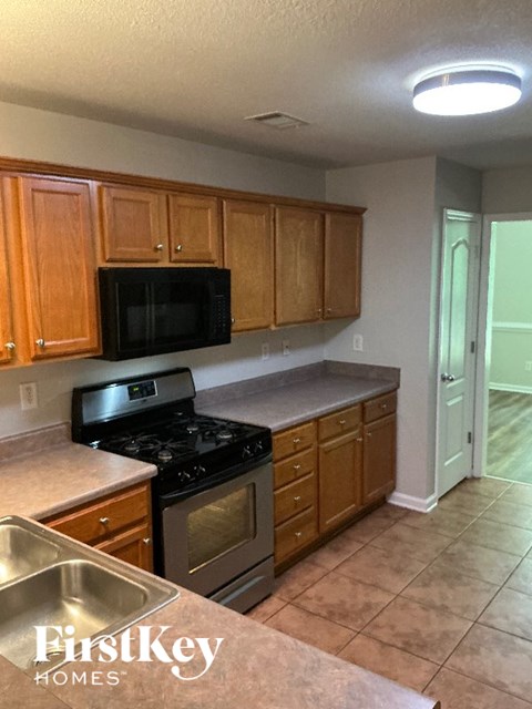 A kitchen with wooden cabinets and a black microwave.