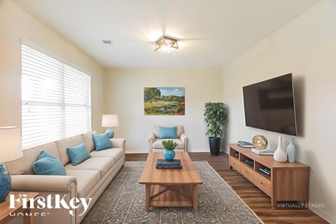 A living room with a couch, a coffee table, a plant, and a painting on the wall.