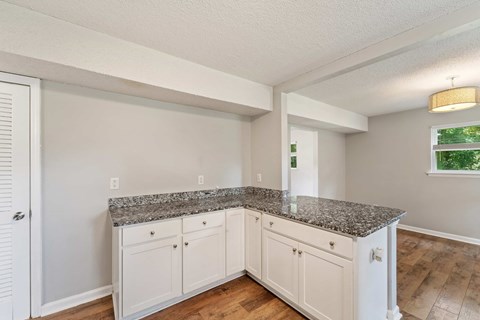 A kitchen with white cabinets and a granite countertop.