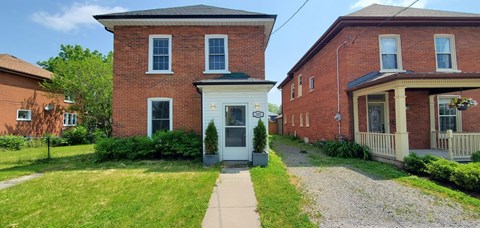 A red brick house with a white door and a small porch.