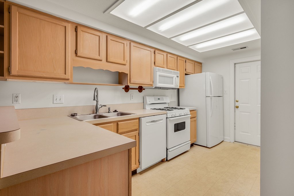 A kitchen with white appliances and wooden cabinets.