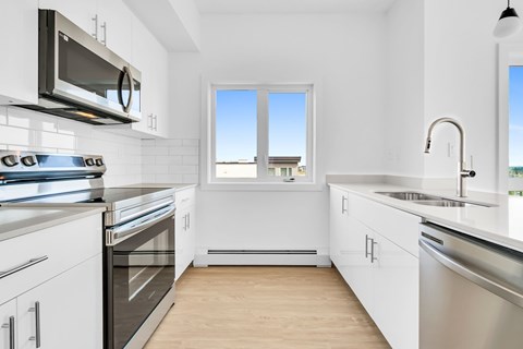 A modern kitchen with white cabinets and stainless steel appliances.