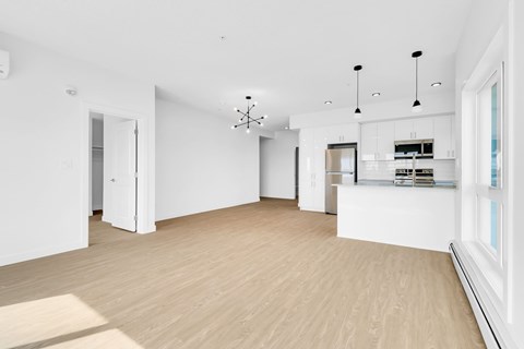 A spacious, empty room with wooden floors and white walls.