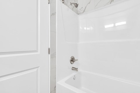 A white bathroom with a tub and a door.