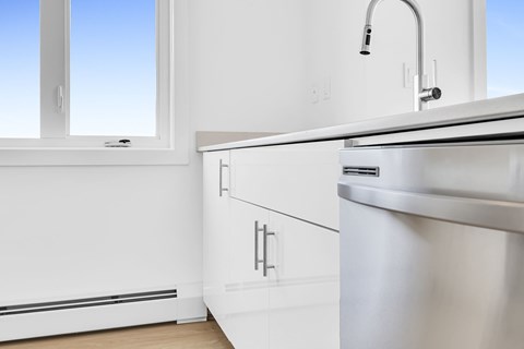 A modern kitchen with a stainless steel sink and white cabinets.