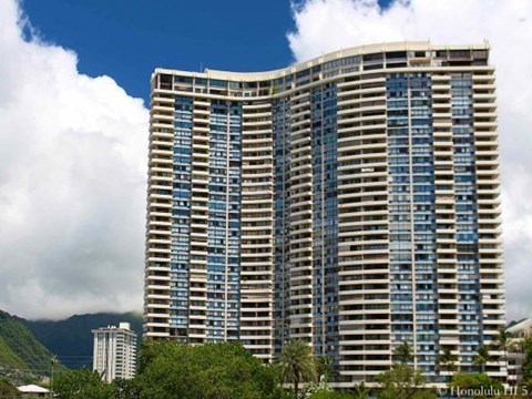 A large building with many windows is in front of a mountain.