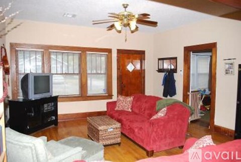A living room with a red couch and a ceiling fan.