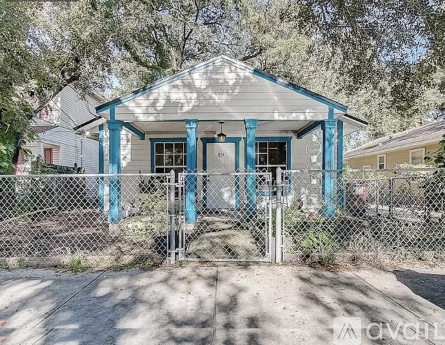 A small house with a porch and a fence in front.