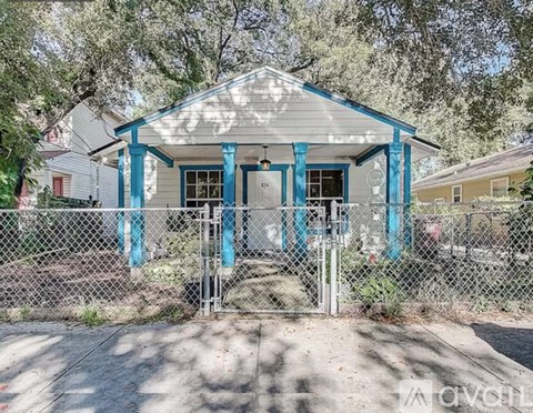 A small house with a porch and a fence in front.