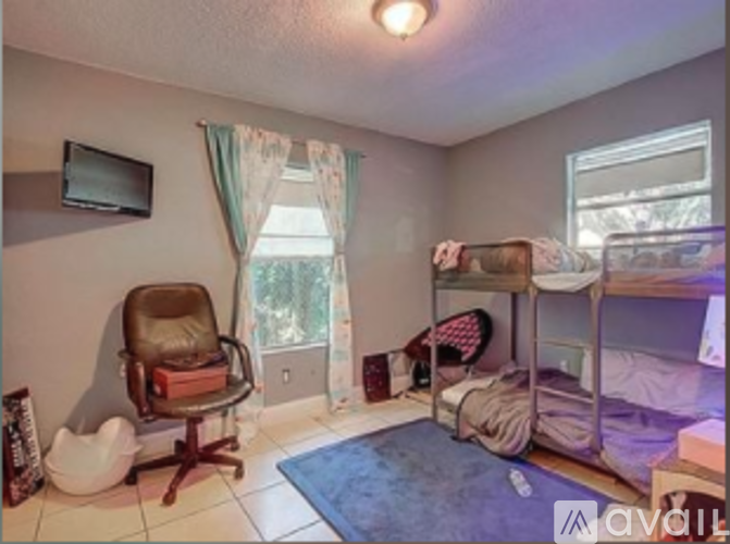 A room with a bunk bed, a chair, and a window.