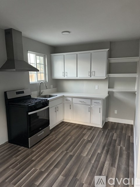 A kitchen with a black stove top oven and white cabinets.