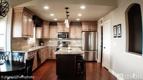 A kitchen with wooden cabinets and a black island.
