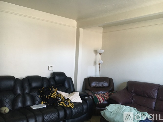 A living room with a black leather sofa and a brown leather chair.