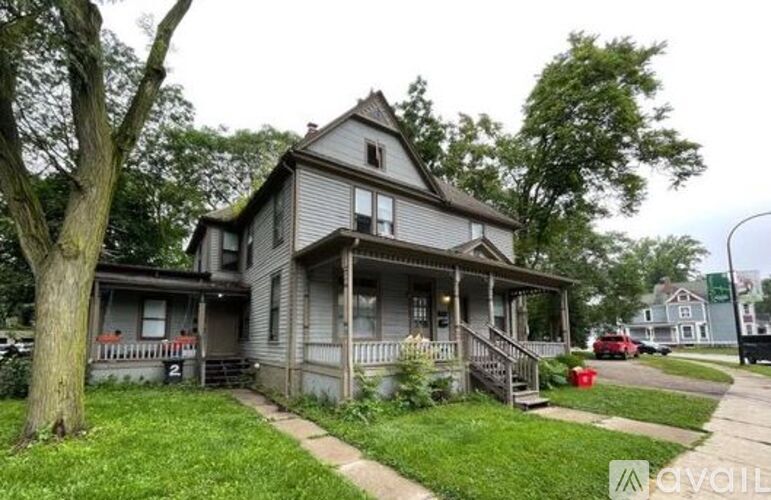 A house with a porch and a tree in front of it.