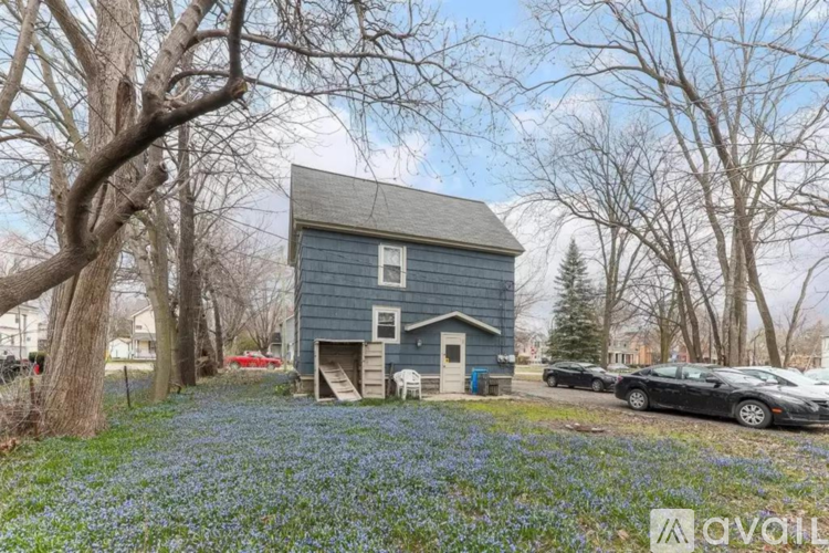 A blue house surrounded by trees and a car parked in front.
