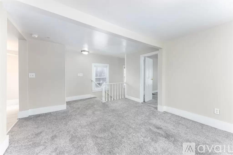 A spacious room with a carpeted floor and a white door.