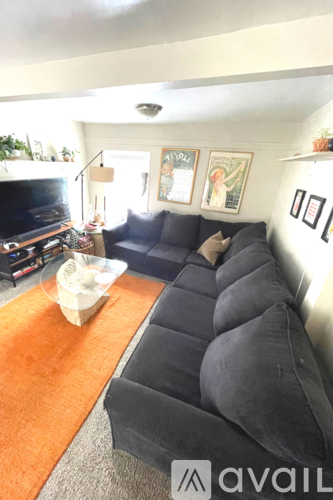 A living room with a black couch and a television.