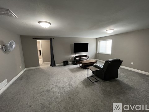 A living room with a black chair and a flat screen TV.