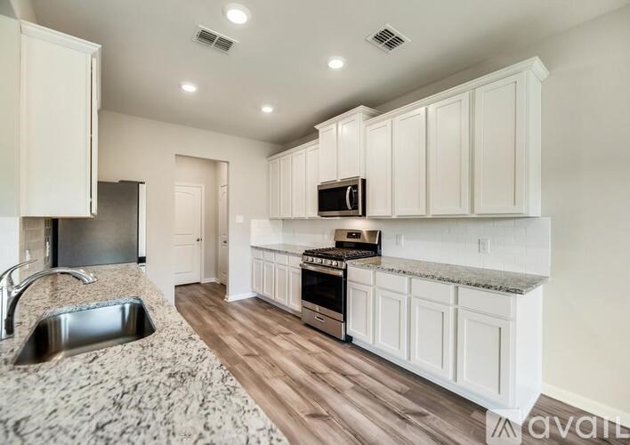 A kitchen with white cabinets and a wooden floor.