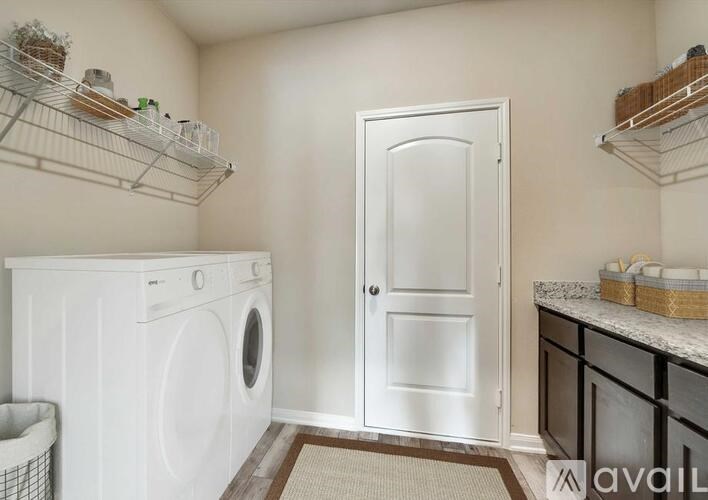 A small laundry room with a washer and dryer, a door, and shelves above the washer.