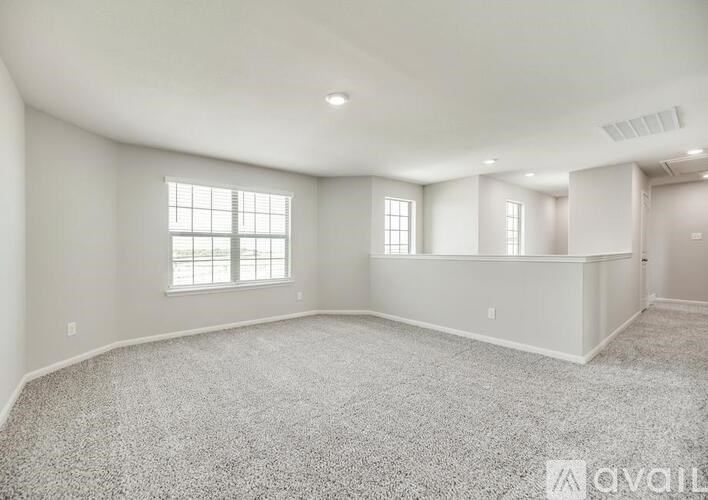 A spacious room with carpeted floor and two windows.