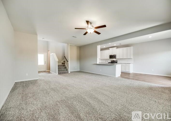 A spacious living room with a carpeted floor and a ceiling fan.