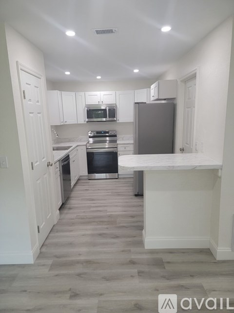 A kitchen with white cabinets and a marble countertop.