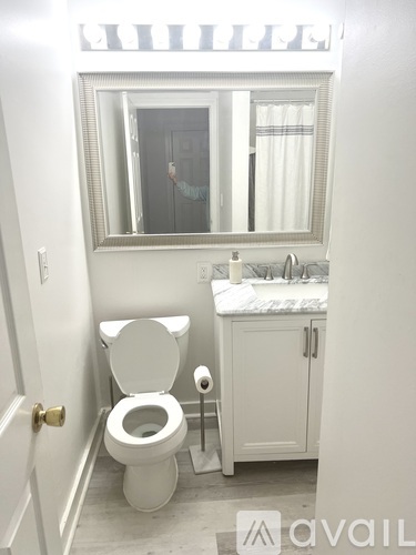 A person is taking a selfie in a bathroom with a toilet, sink, and mirror.