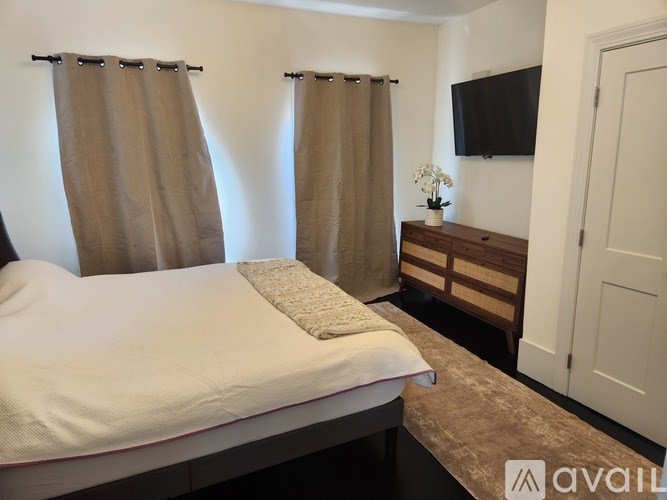 A bedroom with a large bed and a flat screen TV mounted on the wall.
