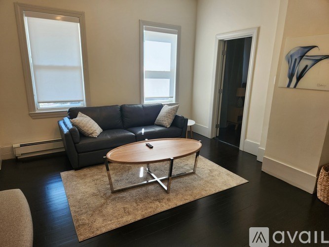 A living room with a black couch and a round wooden coffee table.