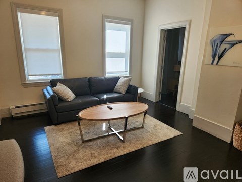 A living room with a black couch and a round wooden coffee table.