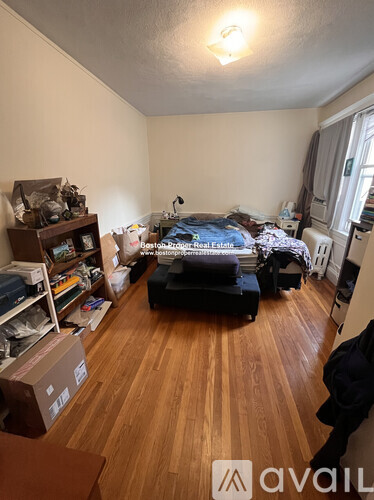 A room with a bed, a couch, and a wooden floor.