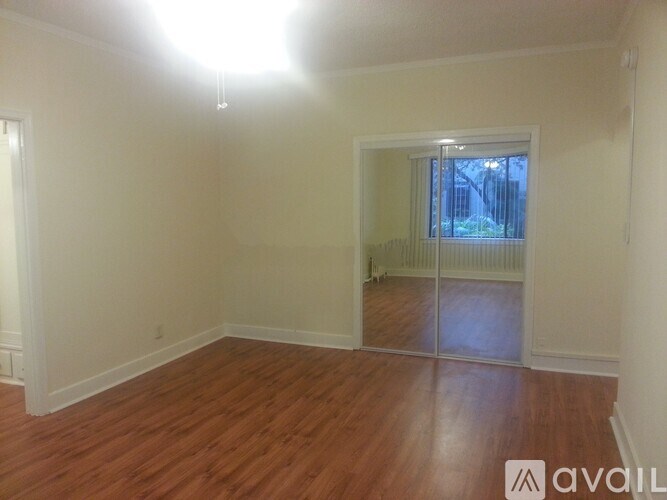 A room with wooden flooring and a window with blinds.